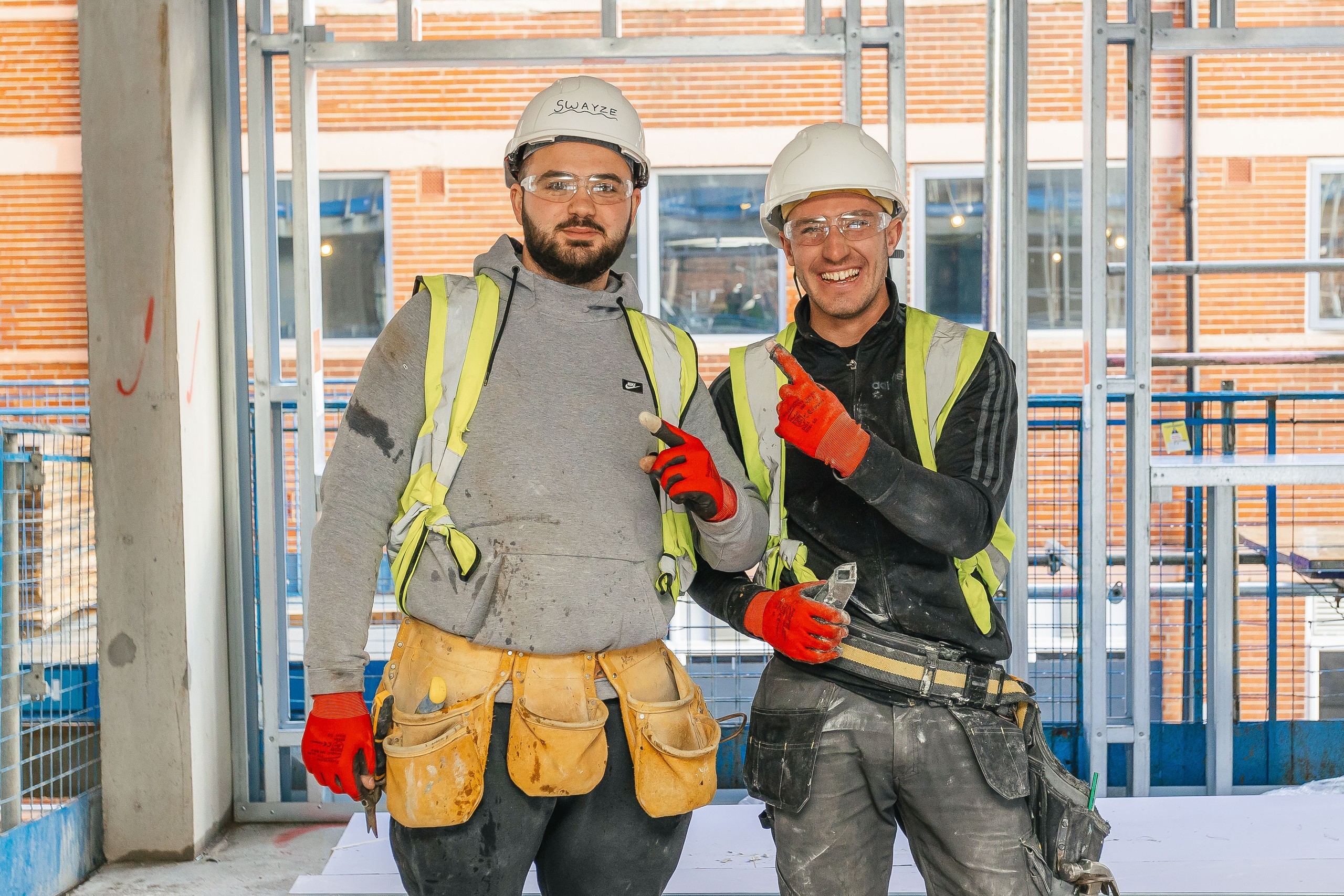 2 construction workers wearing PPE smiling at the camera