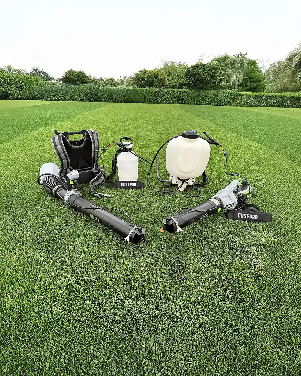 Mist-pro equipment placed on grass, including sprayers and leaf blowers.