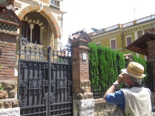 A photo of an iron gate and an arch styled house behind it.