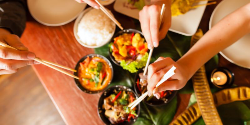 A group of friends eating food with chopsticks