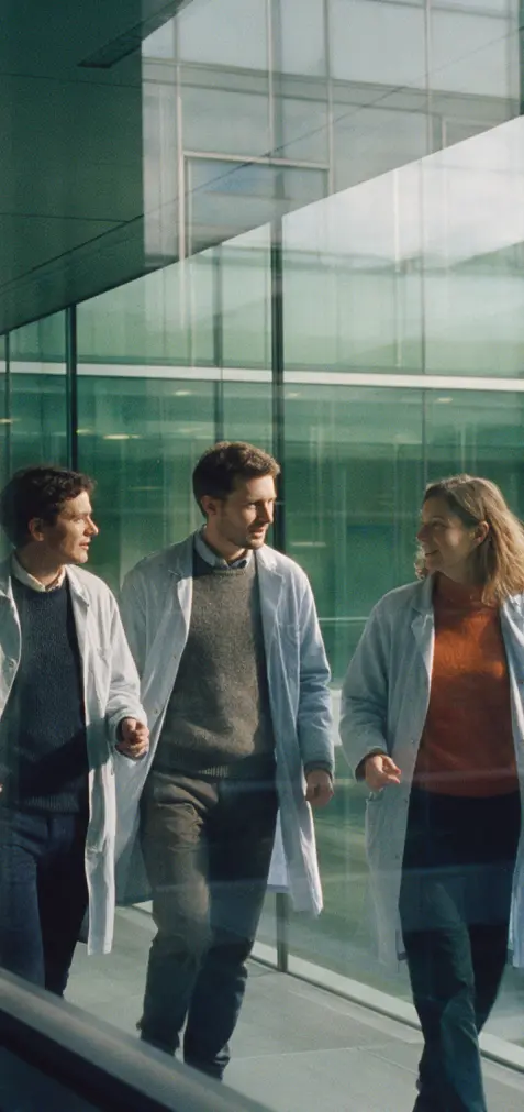 Three healthcare professionals walking past a glass office facade