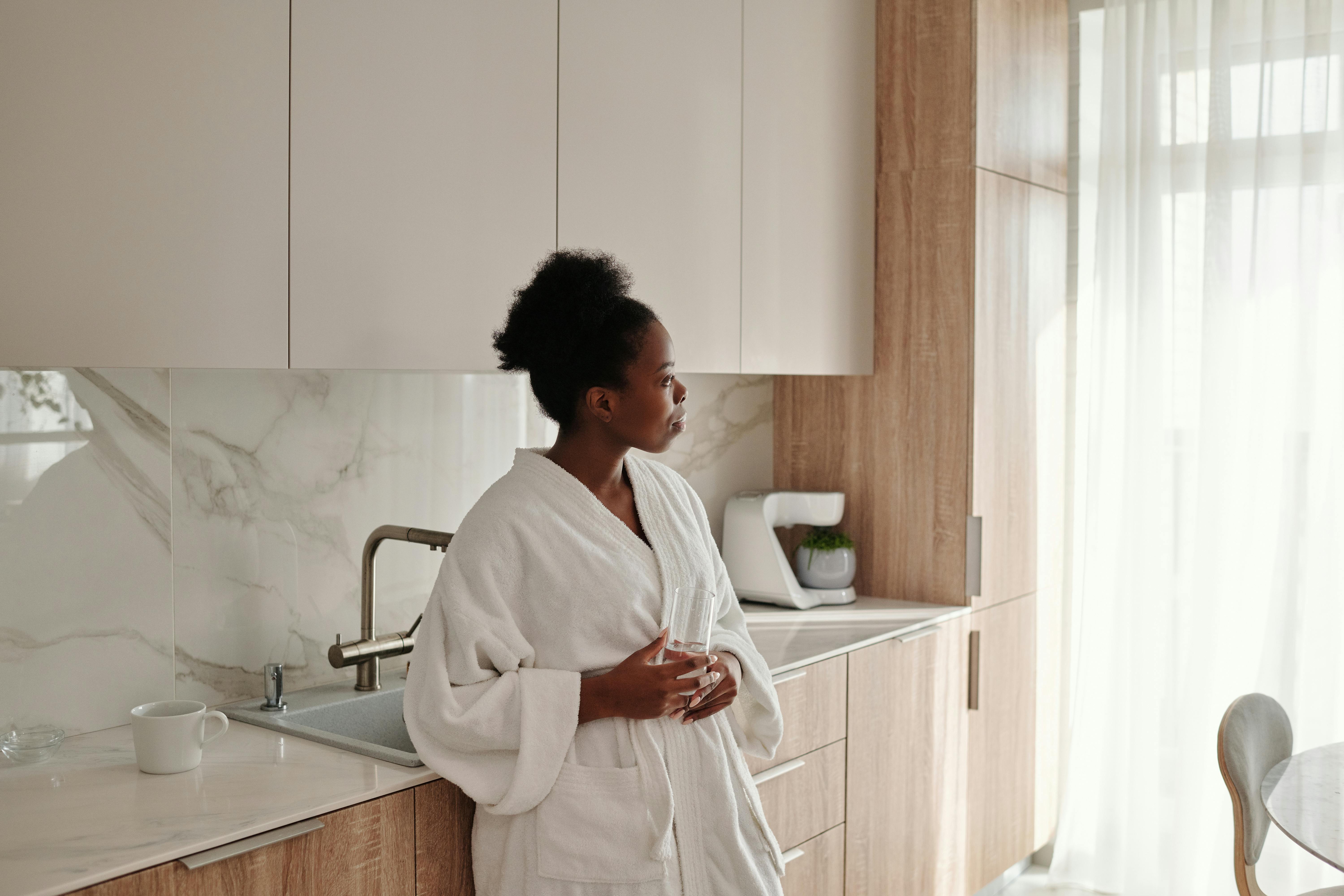 Femme Détendue dans un Logement ANDAS : Cuisine Moderne et Élégante.