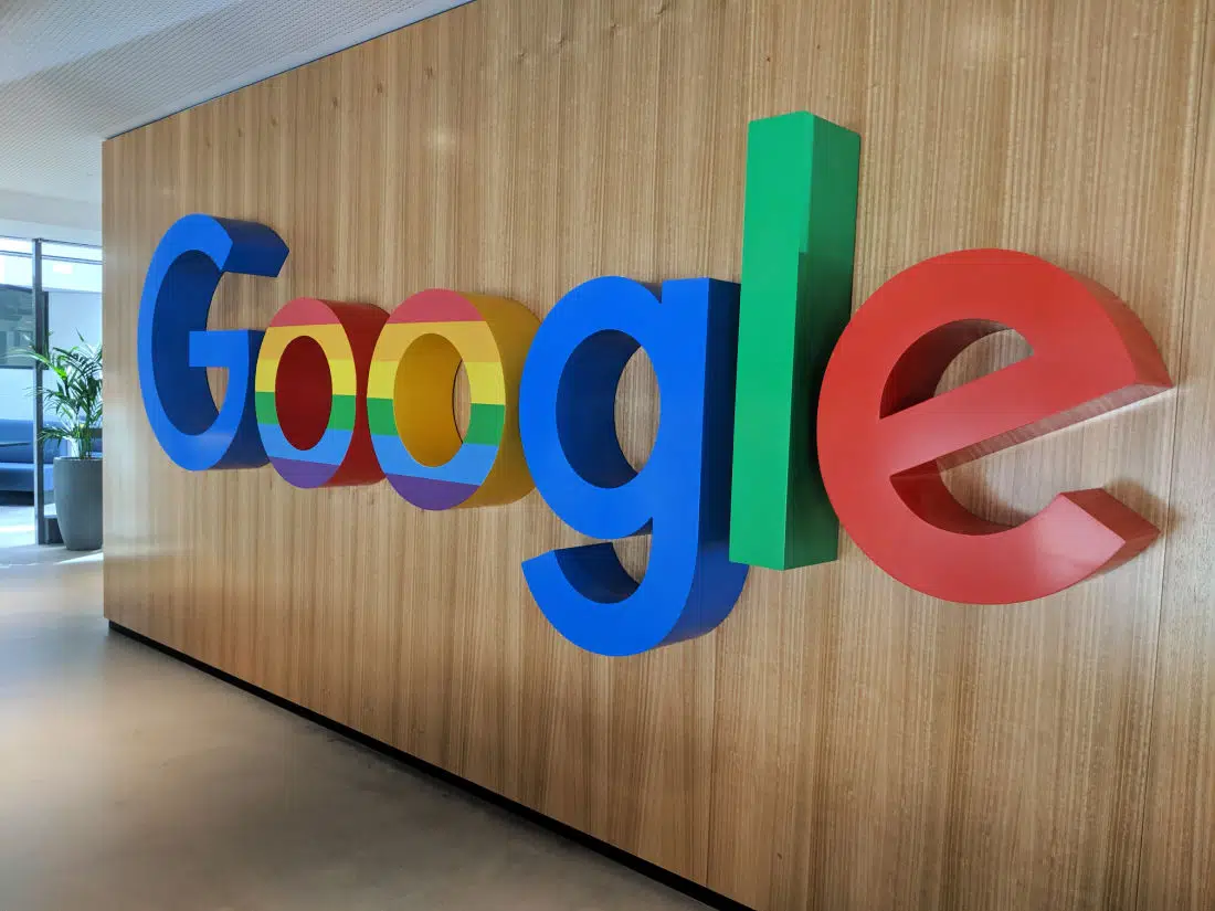 Google logo in blue, red, yellow, and green color, prominently displayed on a wood-like object.