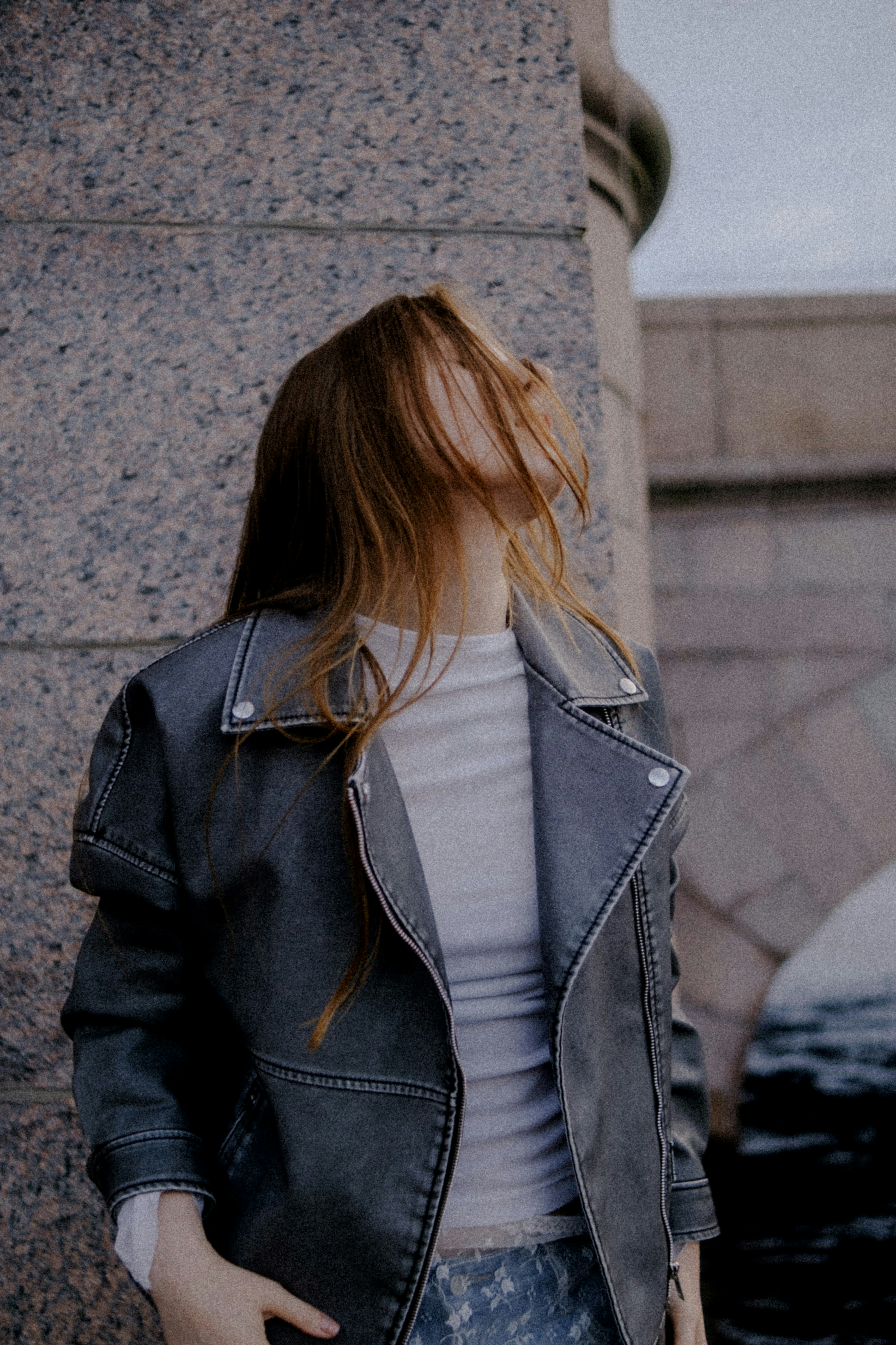 Woman in leather jacket near stone pillar