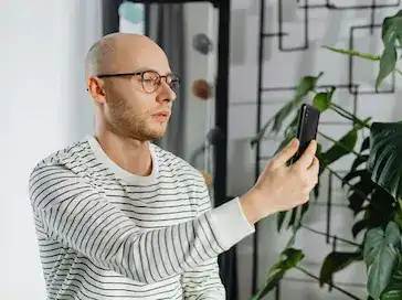 Main d'un homme tenant un smartphone affichant un écran d'appel vidéo actif.