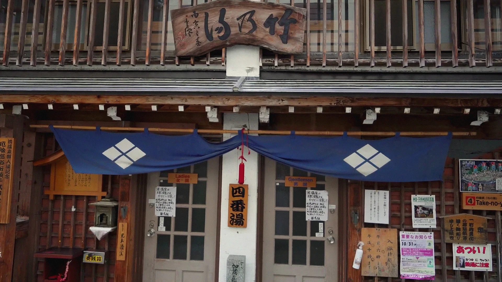 Ryokan facade with a noren curtain lit at night in Shibu Onsen