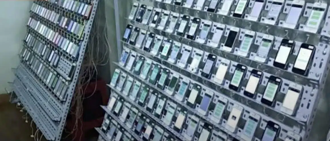 Image from a click farm in which hundreds of smartphones are set up on shelves, ready for use.