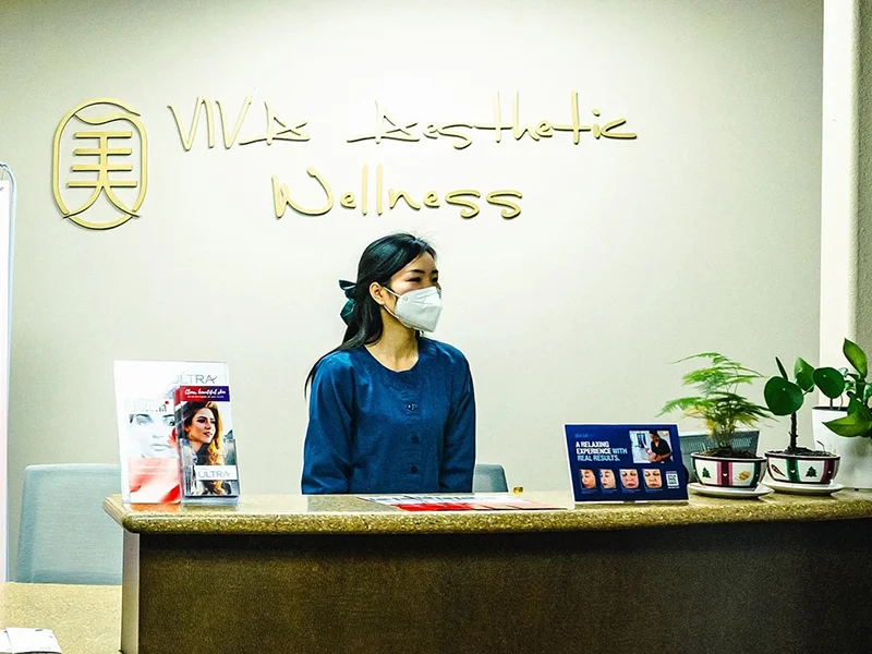 Receptionist wearing mask at Viva Aesthetic Wellness desk.