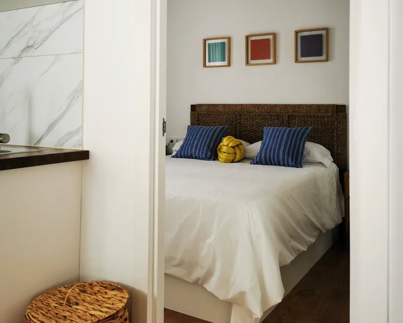 Gemütliches Schlafzimmer mit weissen Bettwäsche und blauen Kissen im La Hipotenusa Tarifa Apartment