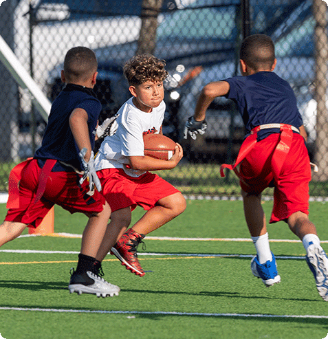 Students practicing passing and catching skills in a structured football enrichment class