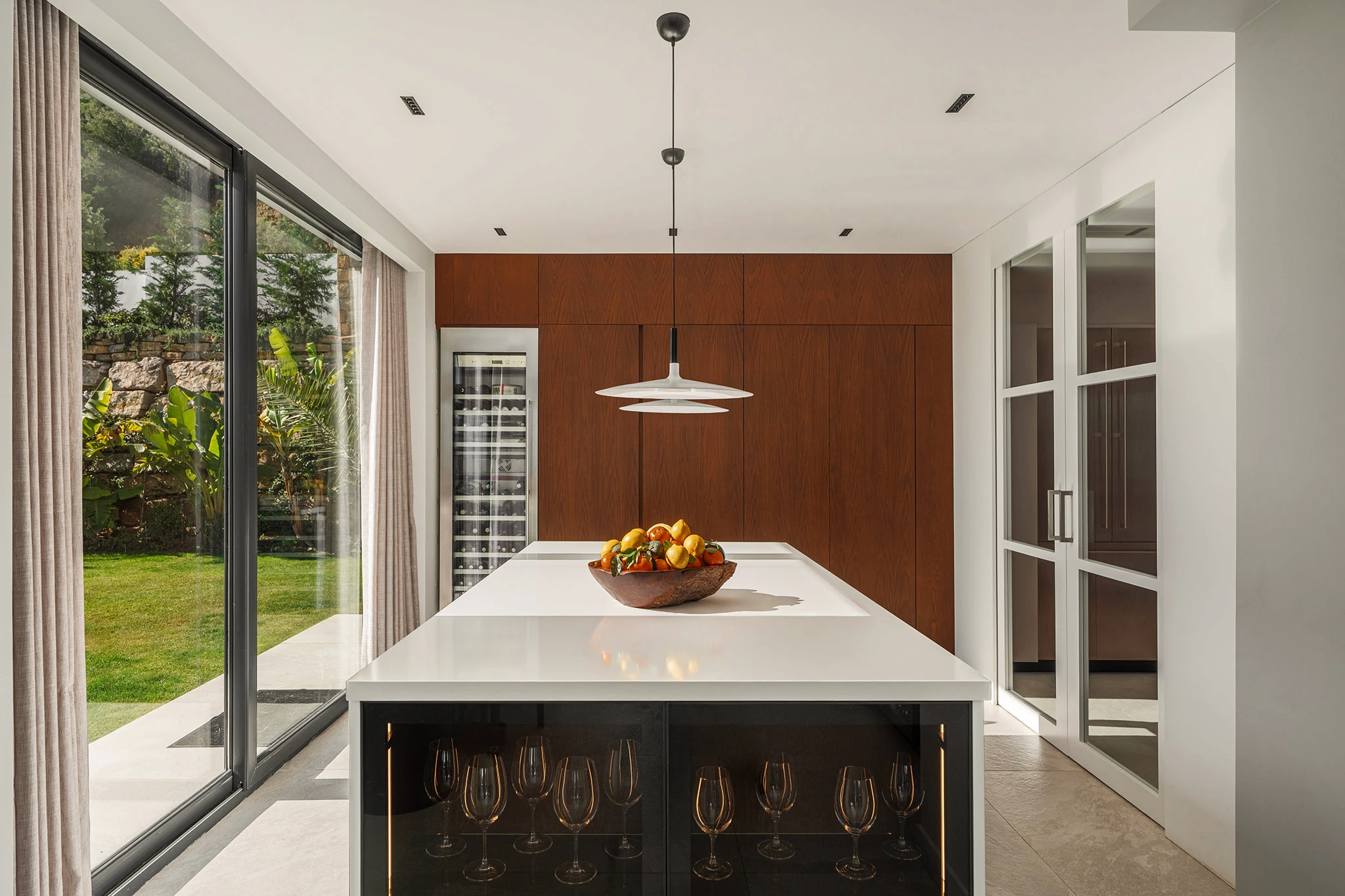 Villa Vista Marbella kitchen with white waterfall island, pendant lighting, and warm wood cabinetry