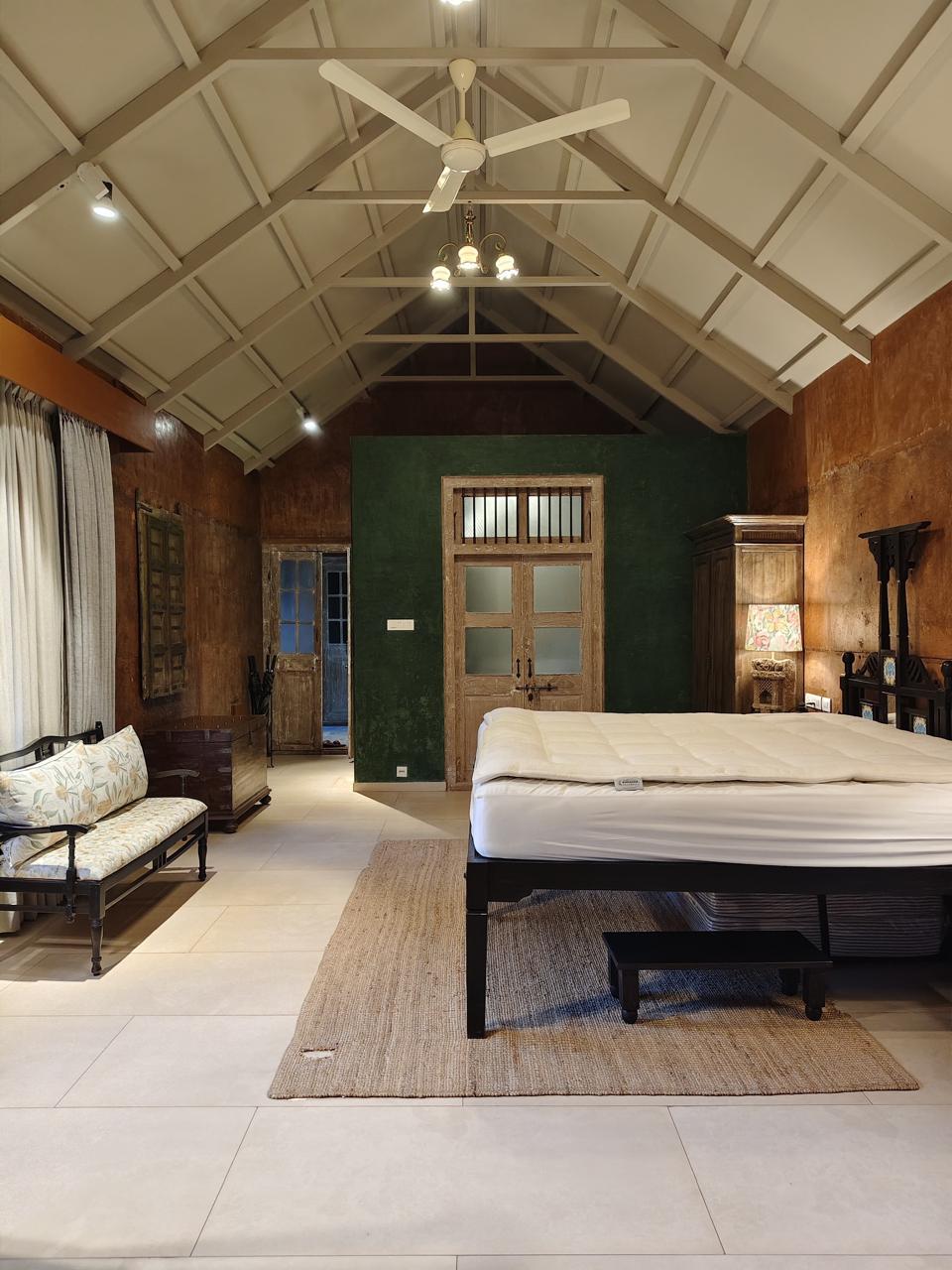 Golden hour architectural courtyard with terracotta walls, overhead beams, and planted walkways lined with trees.