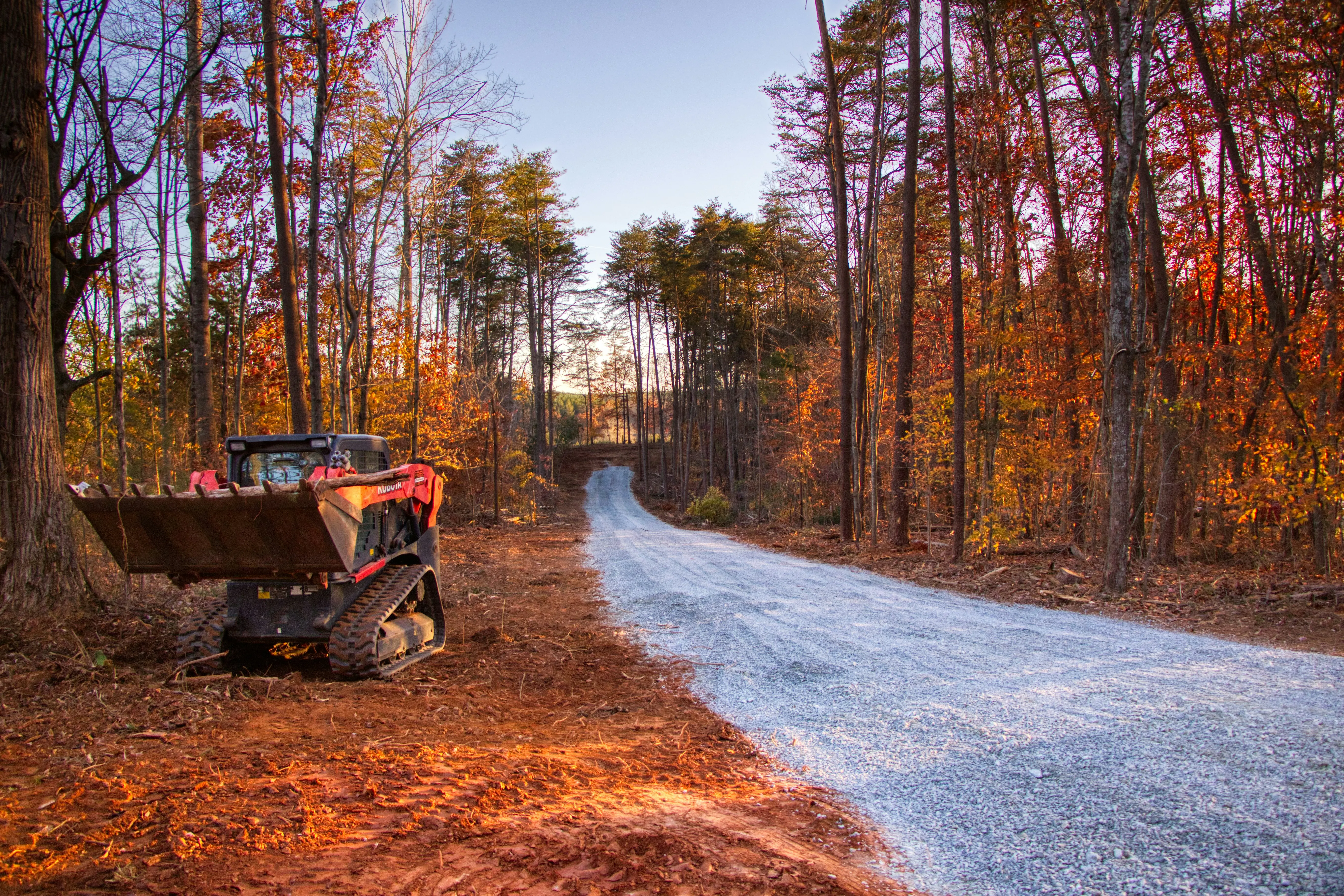 Skid steer loader on a gravel road in autumn forest