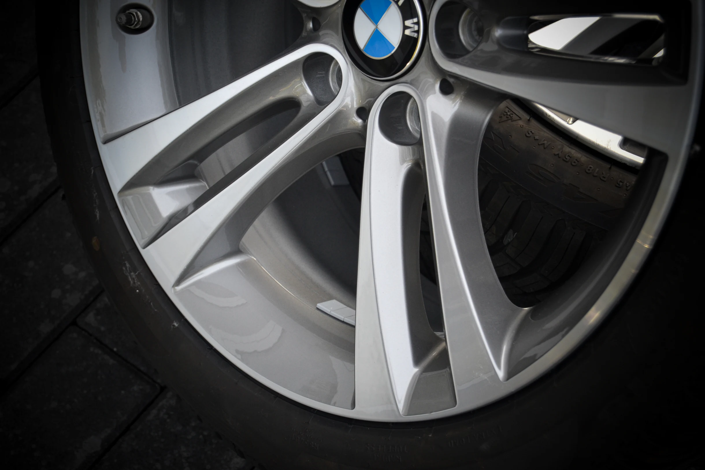 Detail der silberfarbenen Doppelspeichen und des BMW-Nabendeckels bei AT Plus.