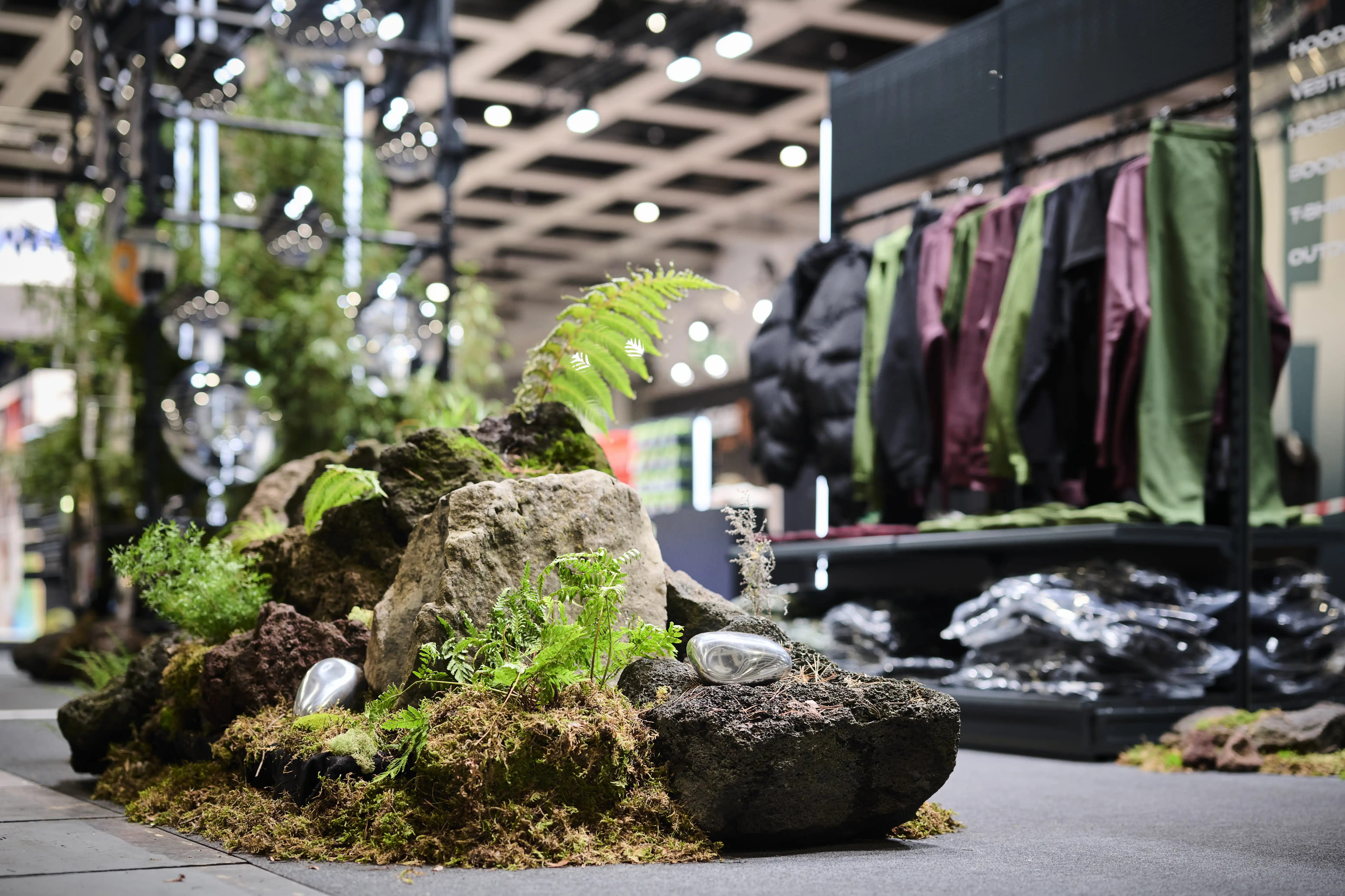 Landscaped island of lava rocks, moss and ferns with silver lures in front of the apparel display at the Nays booth.