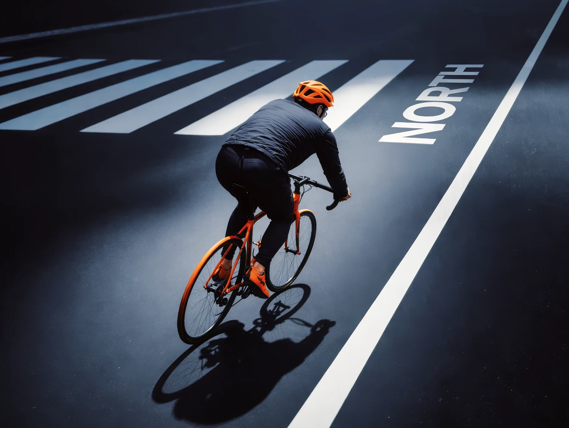 Rear three-quarter view of a cyclist riding an orange North bike along a marked roadway.