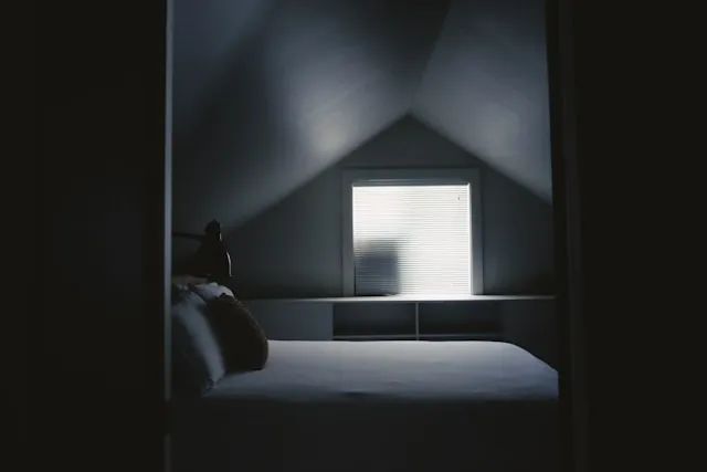 Bedroom at dusk with soft warm light and a calm minimalist setup