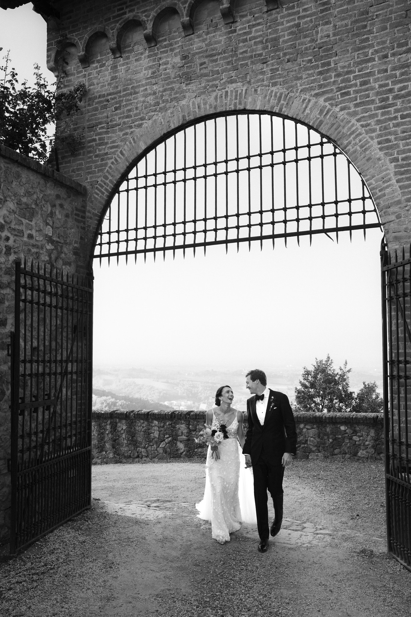 Eline e Antoine attraversano l'arcata in mattoni del Castello di Tabiano, ritratto di matrimonio in bianco e nero