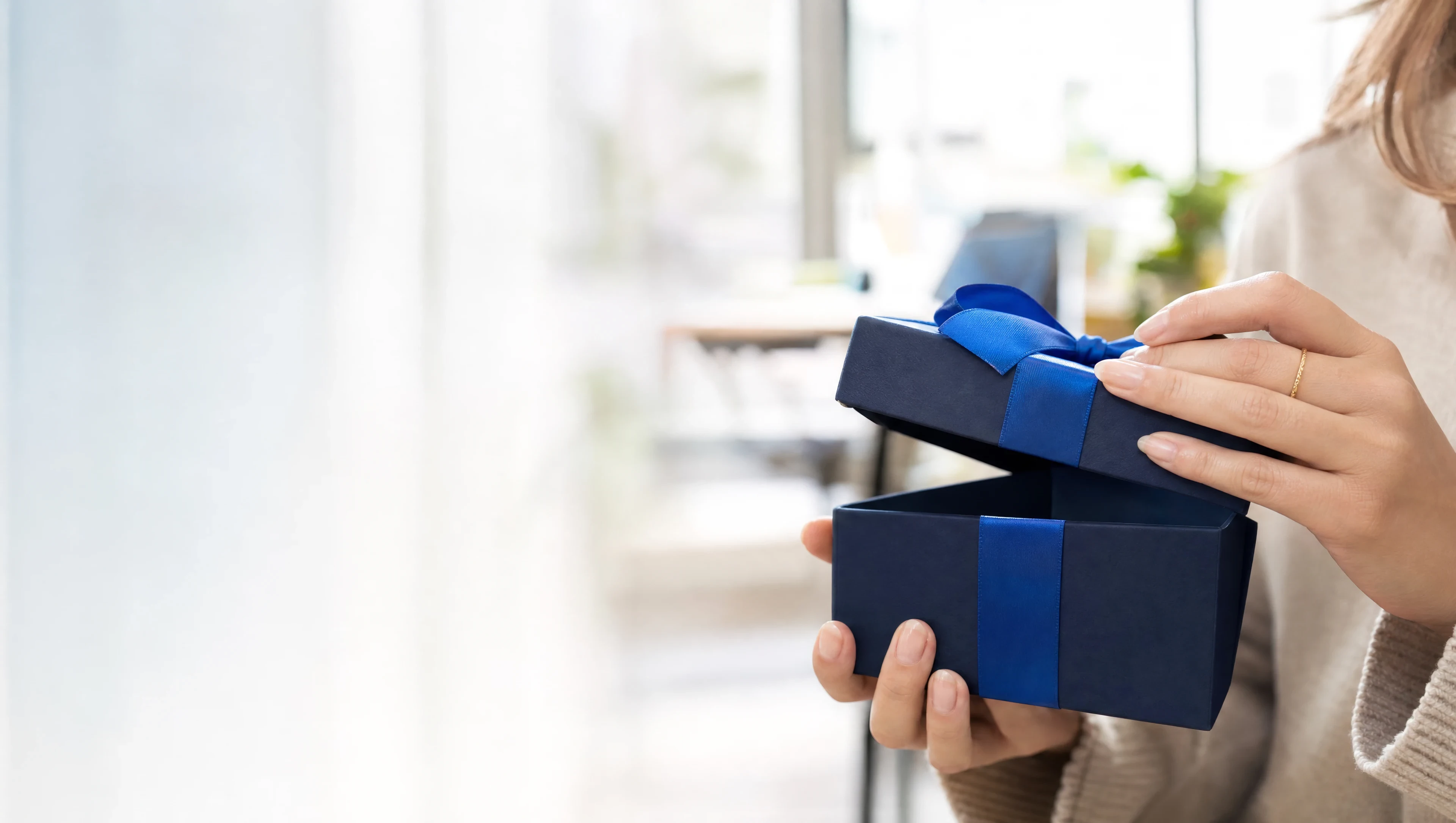 Mãos abrindo uma caixa de presente azul