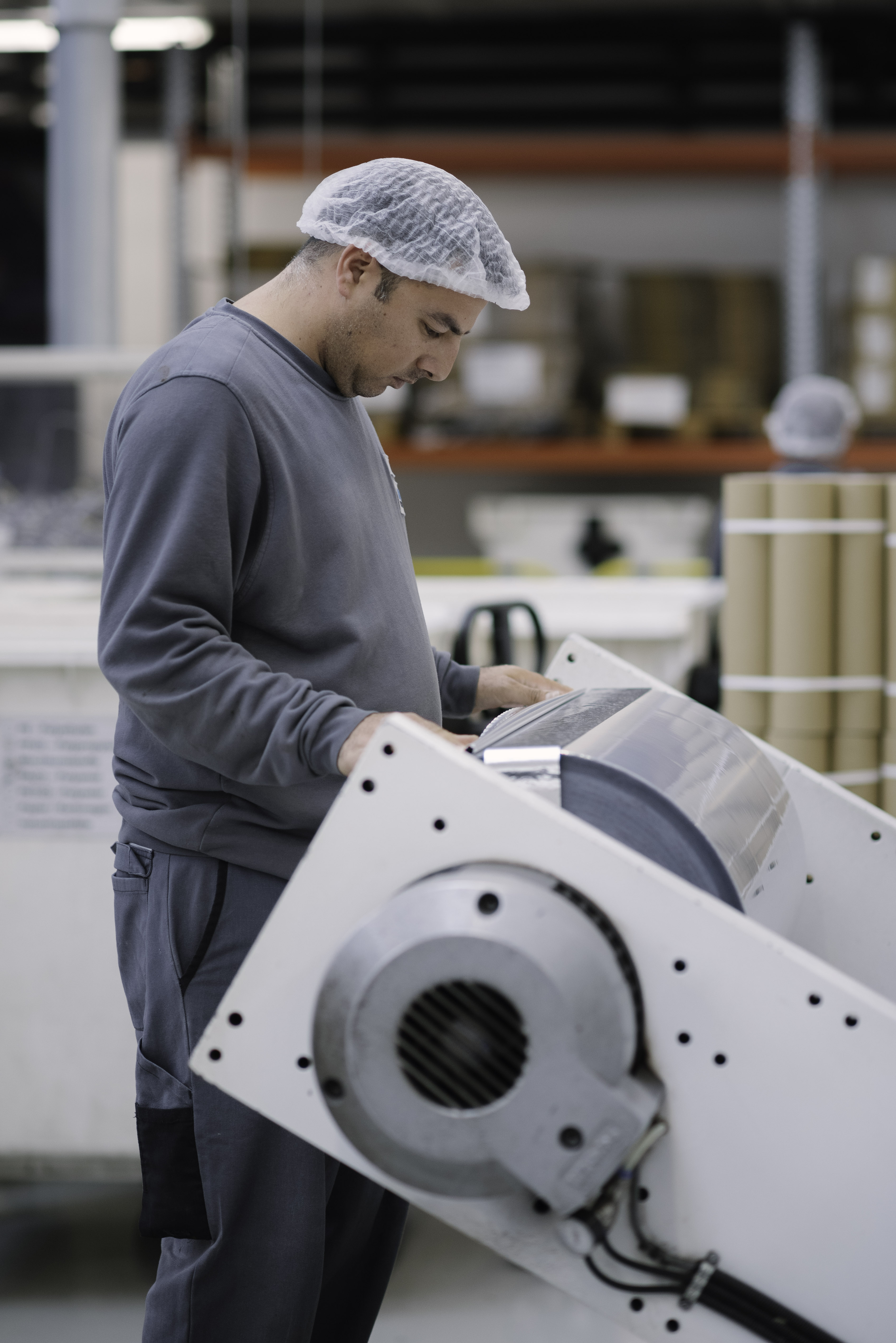 Scheyer employee handling a film reel, preparing it for precise cutting as part of the printing process.