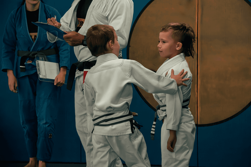 Two young students practicing Jiu Jitsu with an instructor observing