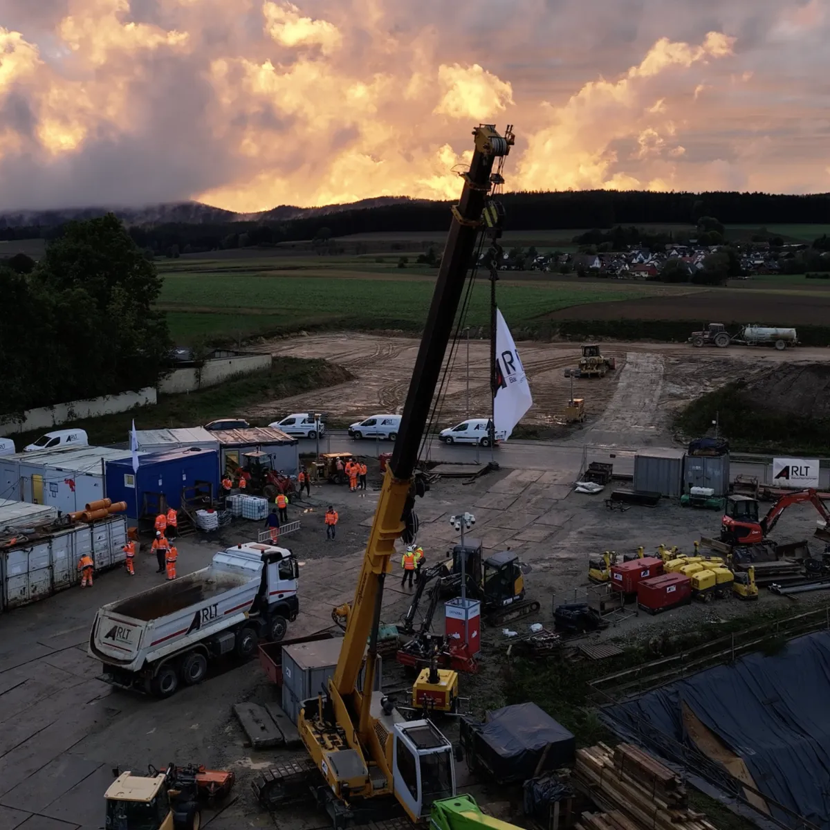 Baustelle mit Baggern und Kränen. Im Hintergrund der Sonnenuntergang.