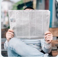 person wearing suit reading business newspaper