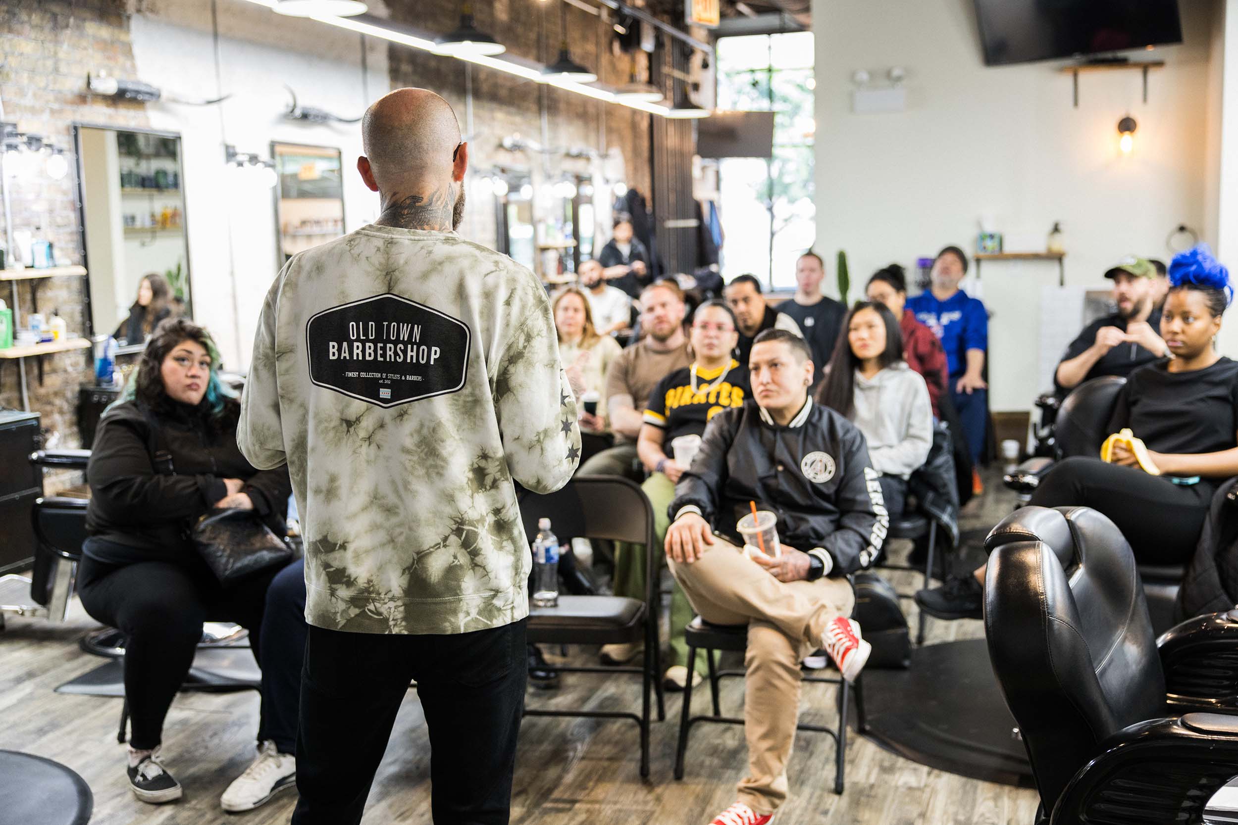 Old Town Barbershop owner addressing a crowd of barbers and stylists inside the shop in Chicago IL