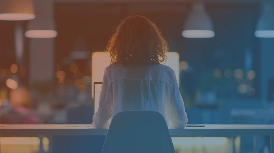woman sitting at computer in dimly lit office