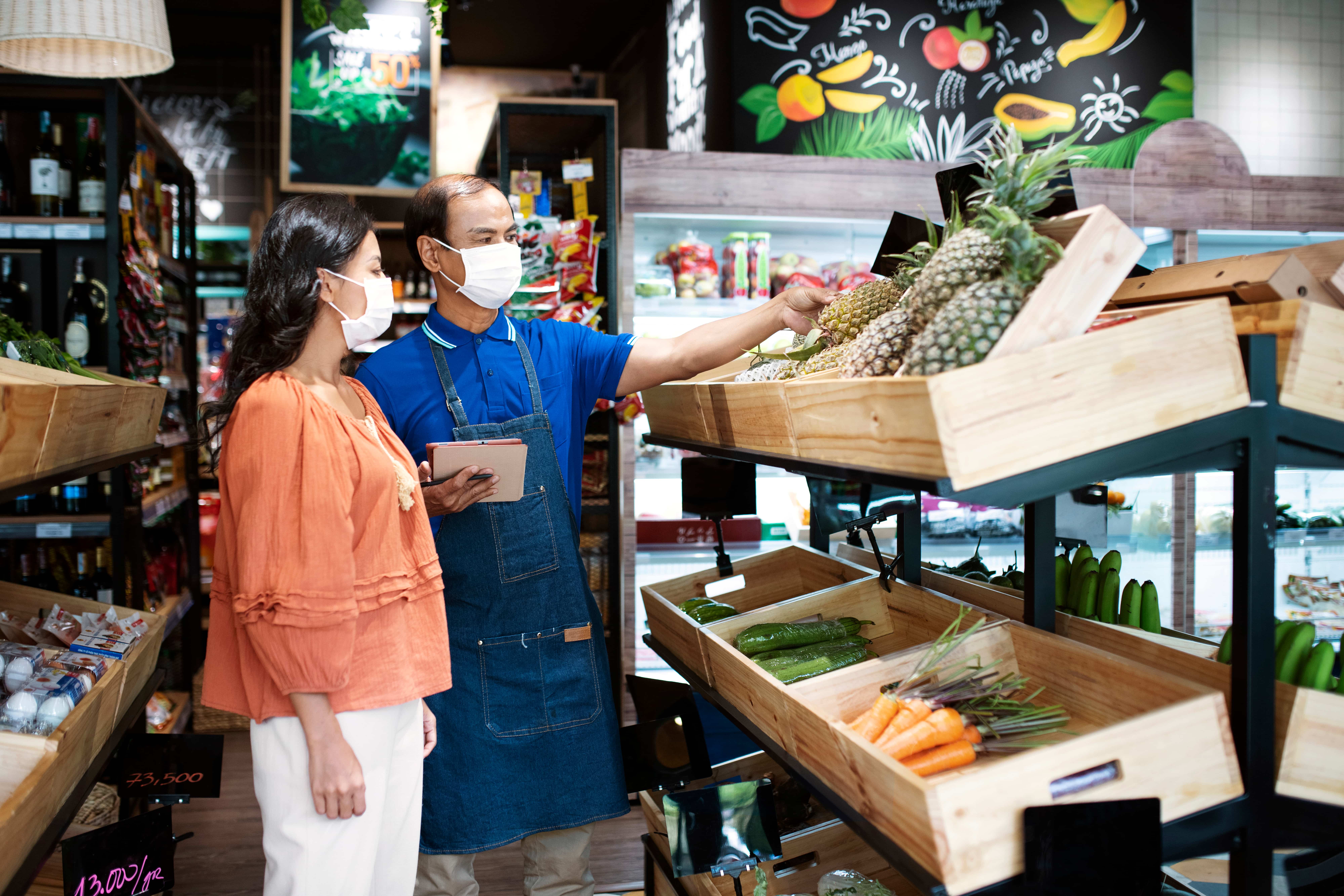 A seller helping a woman choose pineapples