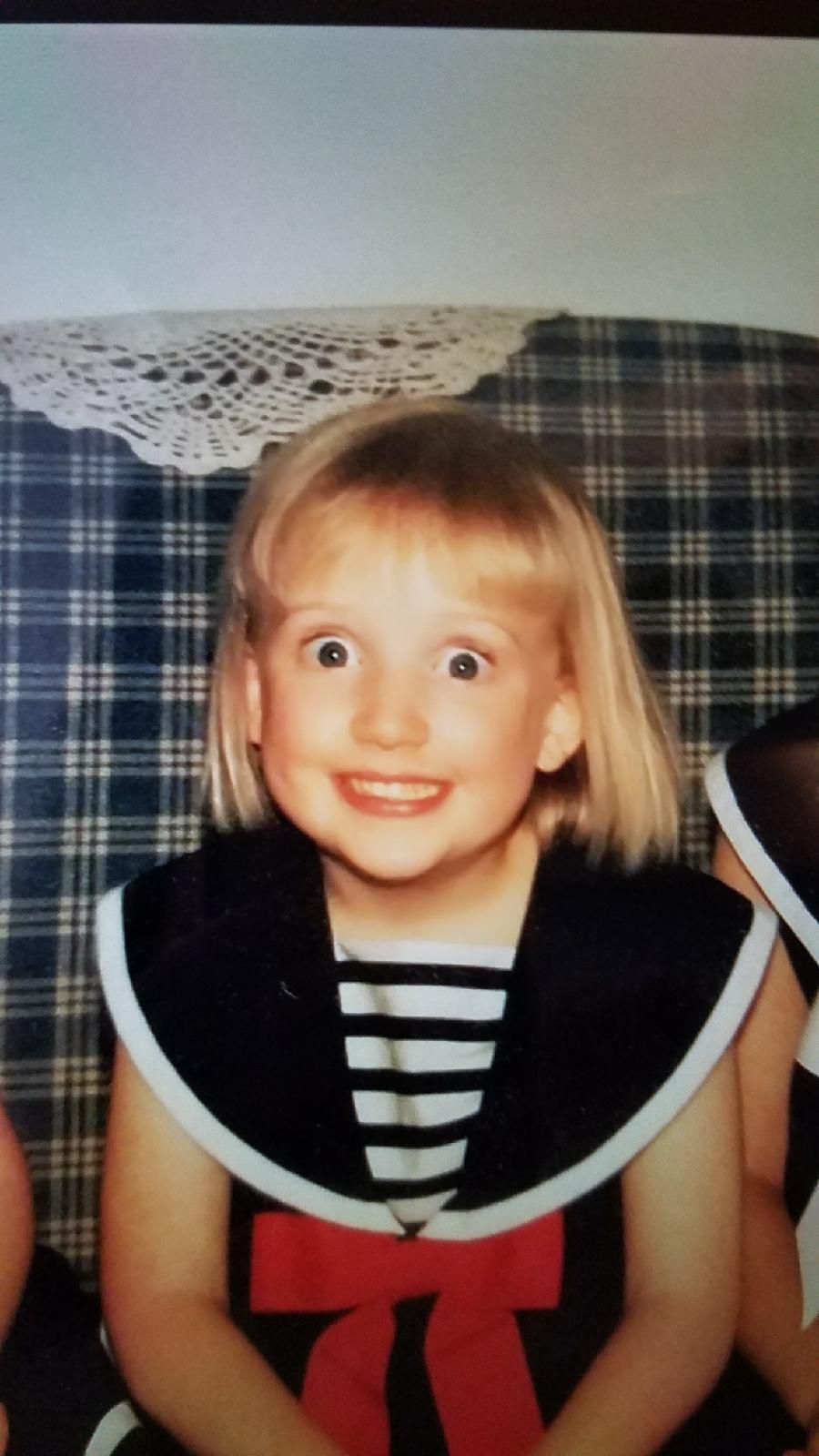 Childhood photo of Elise with silly wide eyes and a fancy outfit