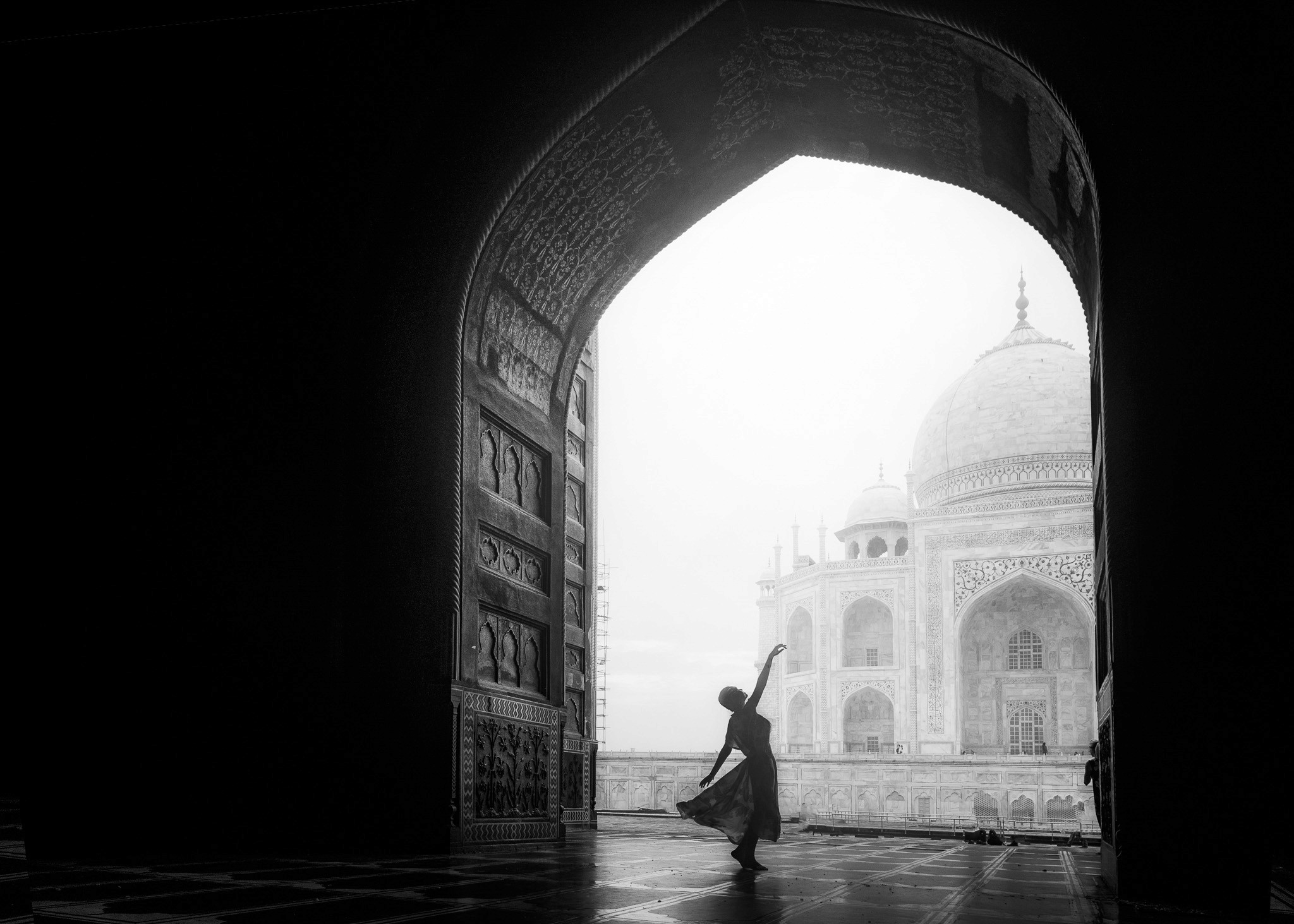 A man shining a light into the sky standing on rocks at the edge of a lake