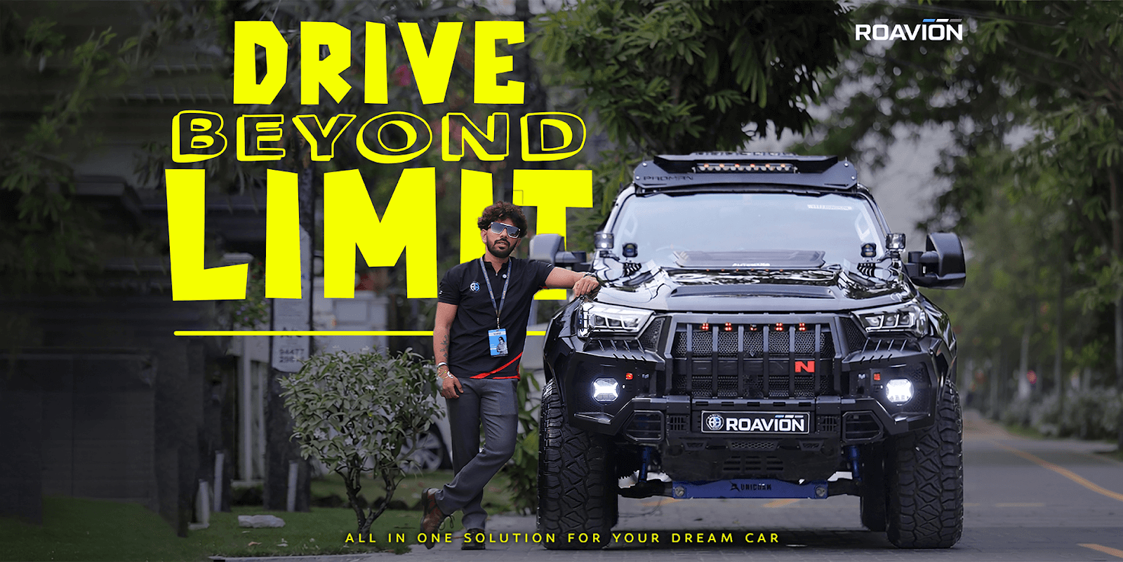 A man stands beside a modified black SUV with bright lights, promoting "Drive Beyond Limit" for Roavion Automotive.