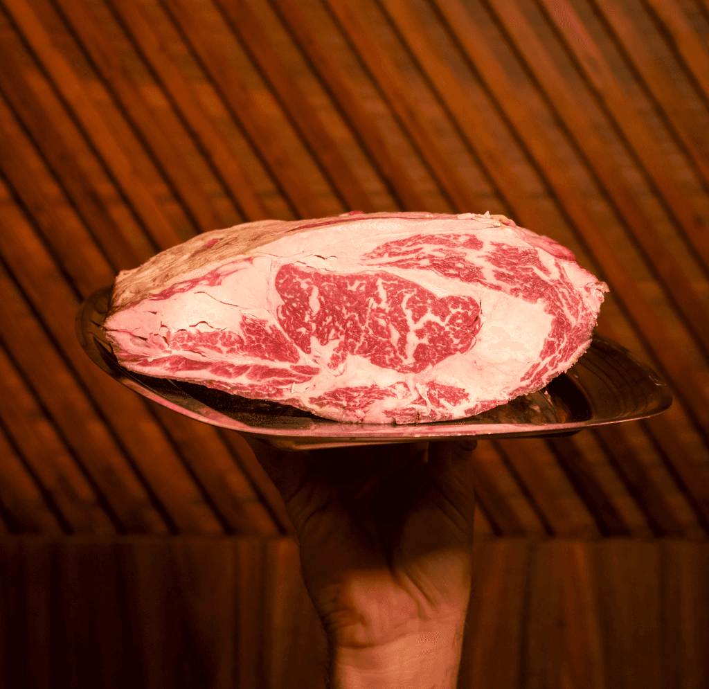 A luxurious bathtub filled with water and floating rose petals, surrounded by candles and greenery. The soft lighting creates a tranquil and romantic spa-like atmosphere.