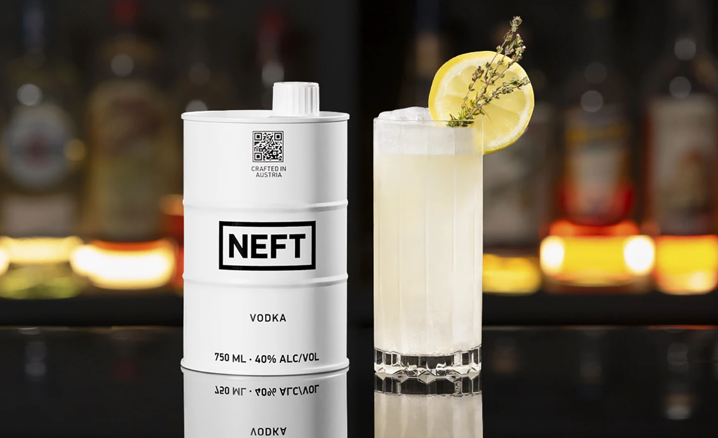 A NEFT Vodka Barrel and a glass of Summer Thyme Lemonade on a bar counter.