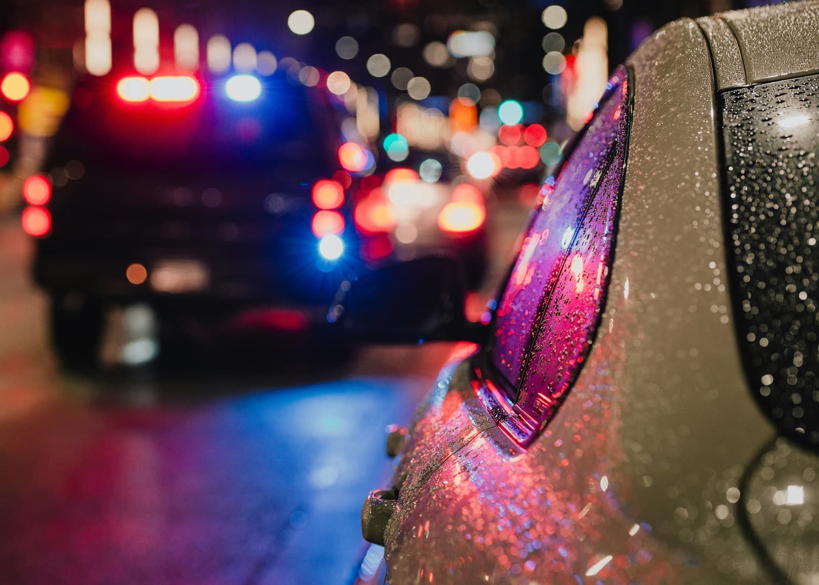 Police car stopping a vehicle on a rainy city street at night