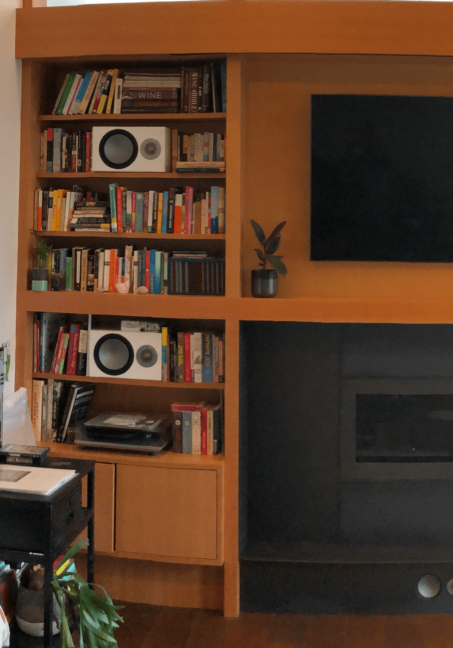 A detail of a wooden bookcase with books and audio equipment in a den.