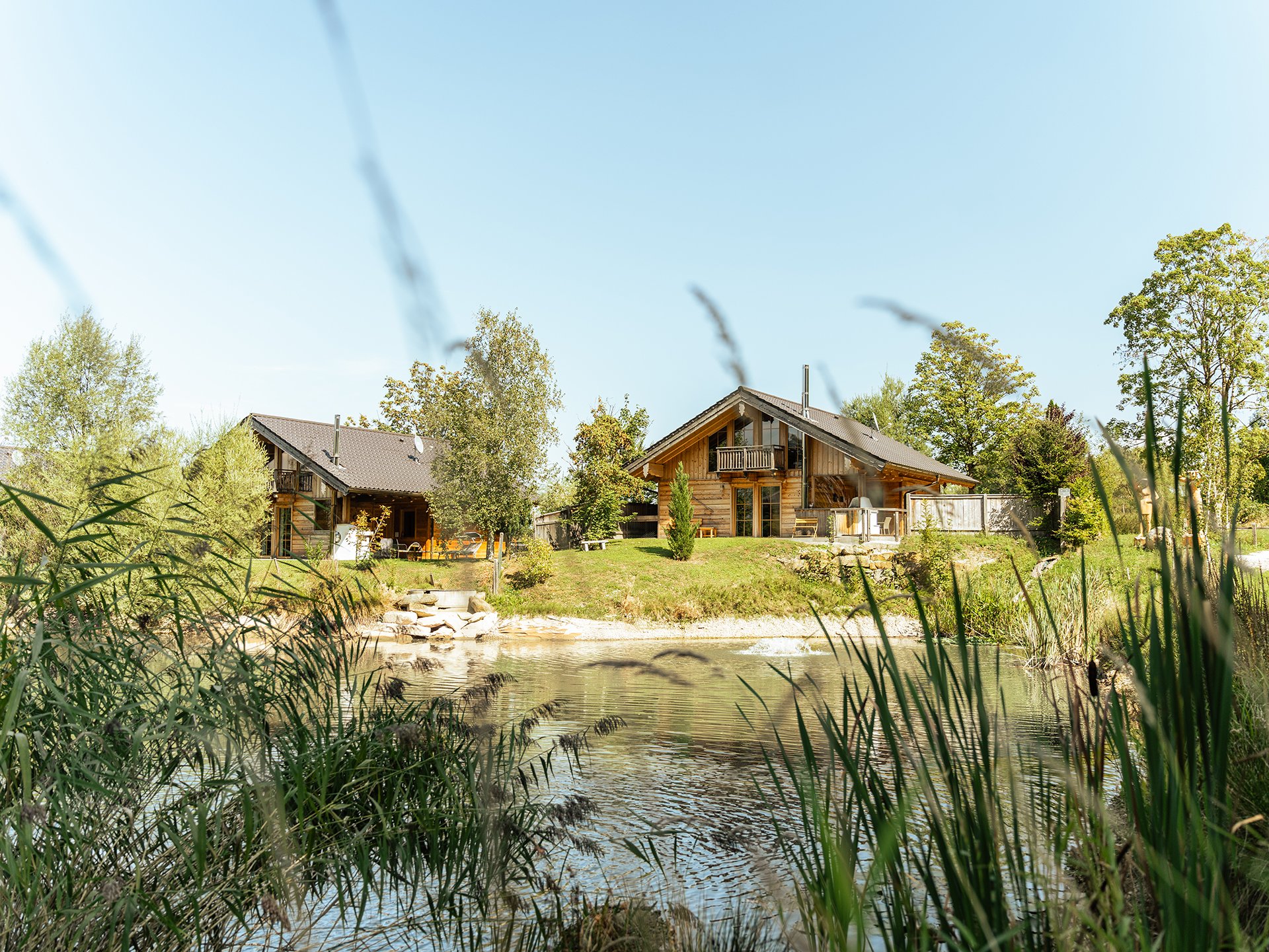 Bayern Chalets mit Teich und umgeben von Grün.