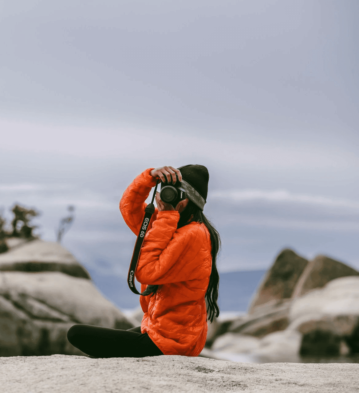 Woman crouching on rocks taking a photo