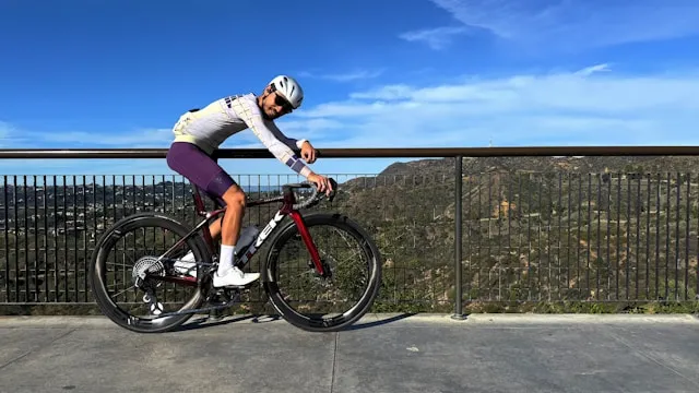 Cyclist pausing on a mountain overlook with a road bike and open landscape