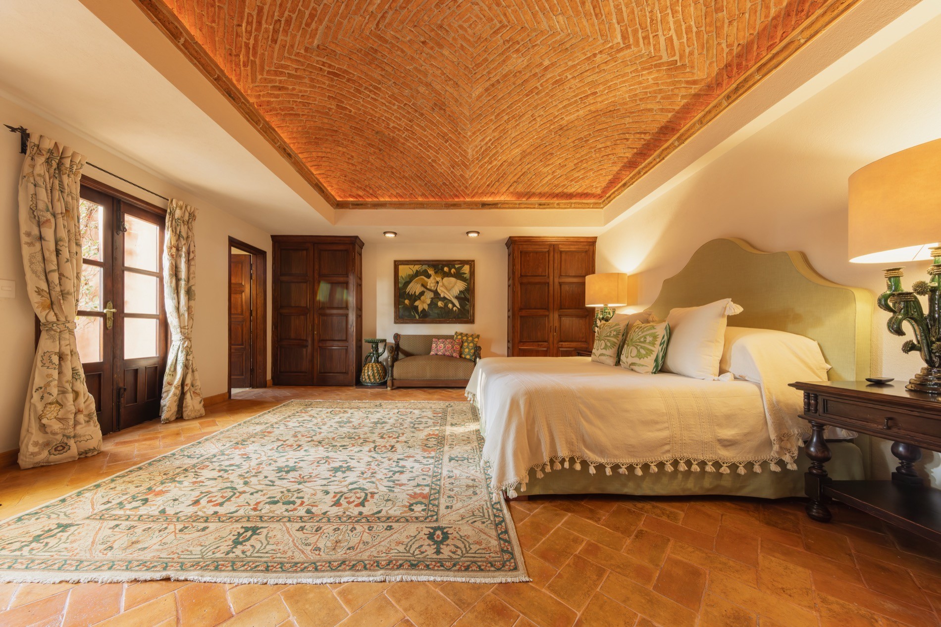 La Residencia guest bedroom with boveda ceiling, fireplace, and garden-view windows
