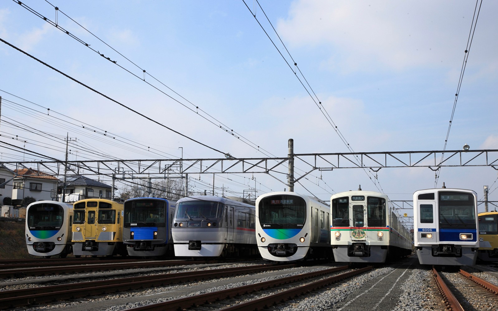 Seibu Railway trains lined up on tracks under a clear sky in Japan.