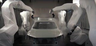 Mehrere umhüllte Lackierroboter in einer Fahrzeuglackierkabine
