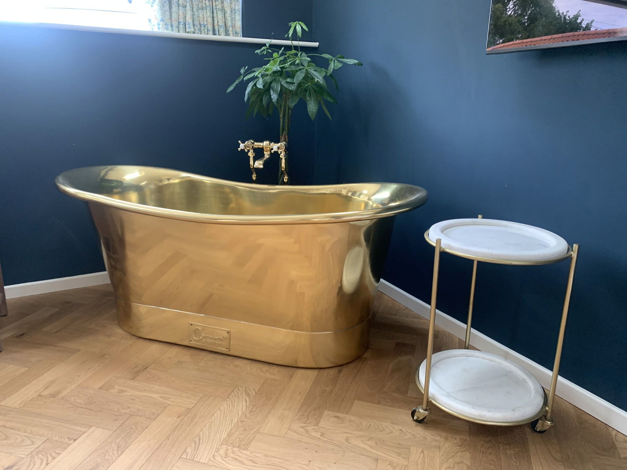 Luxury gold bath in blue bathroom with wooden floor