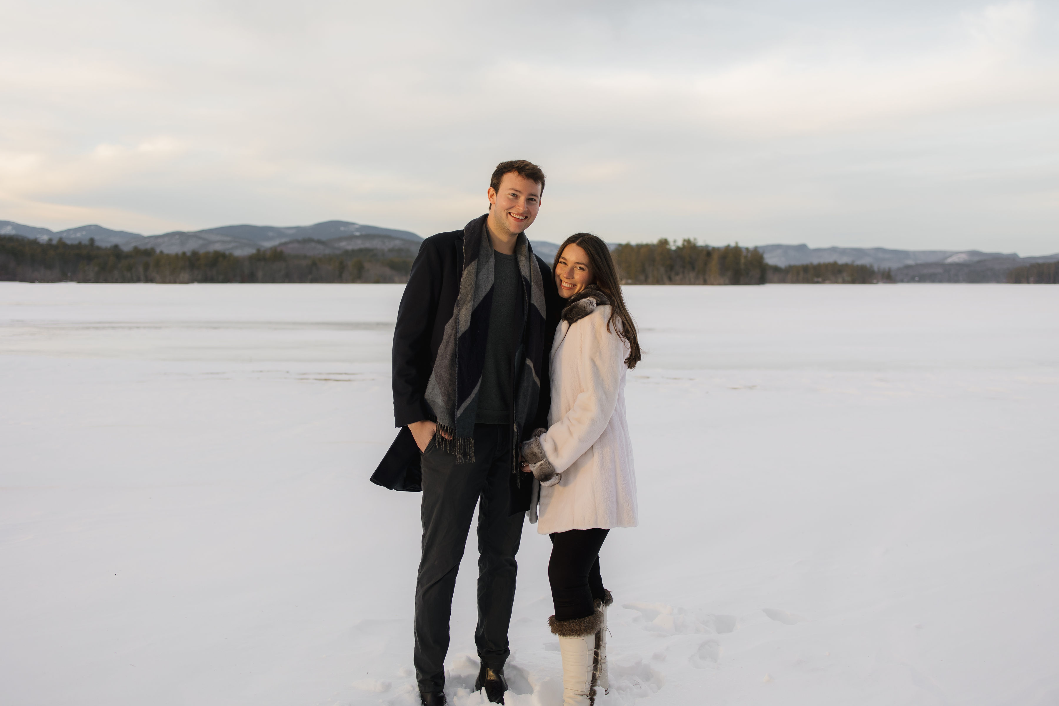 A couple stands outdoors at sunset.