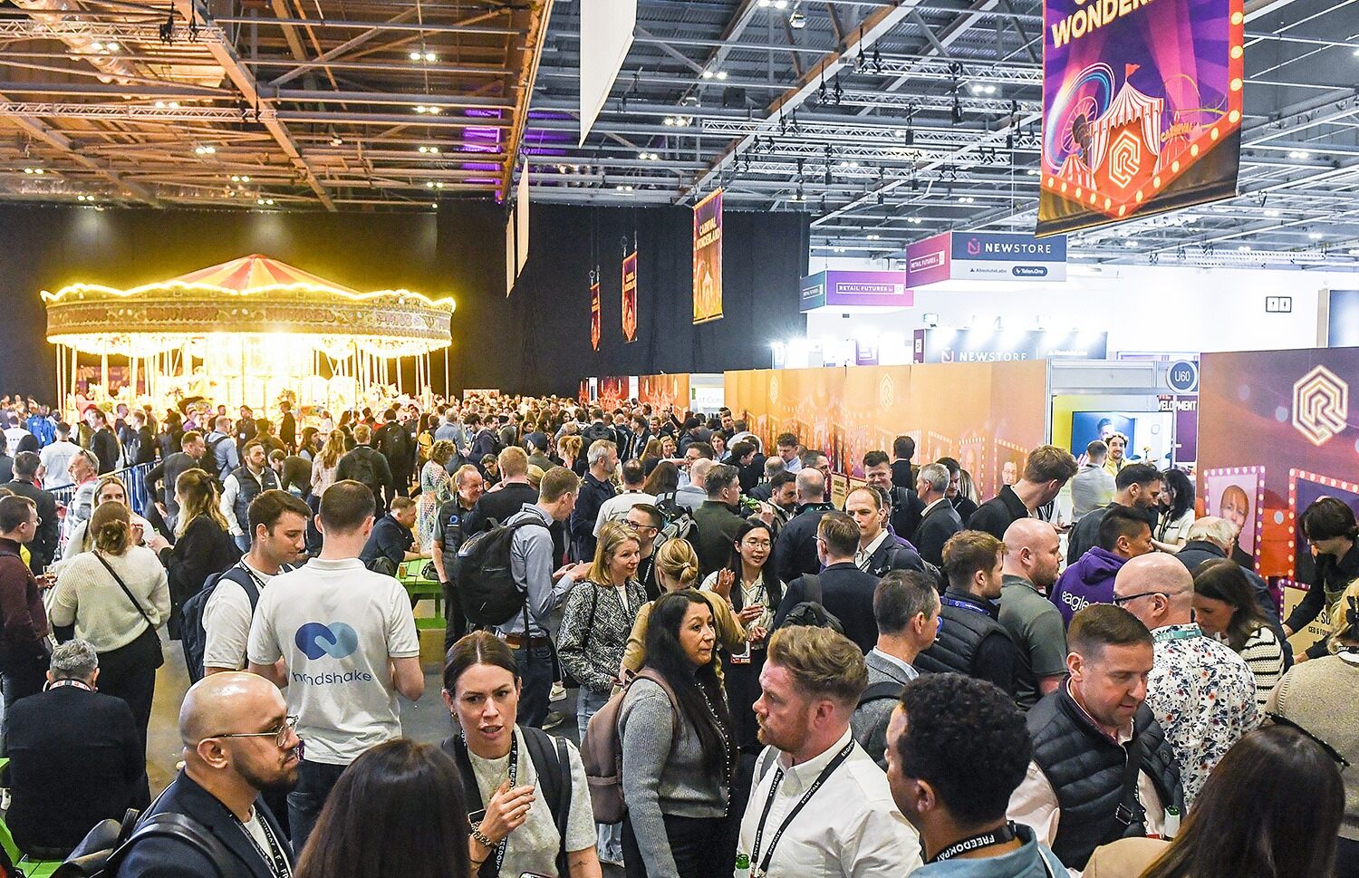A large truck parked on a street with a bright pink carpet leading up to it, surrounded by people and trees.