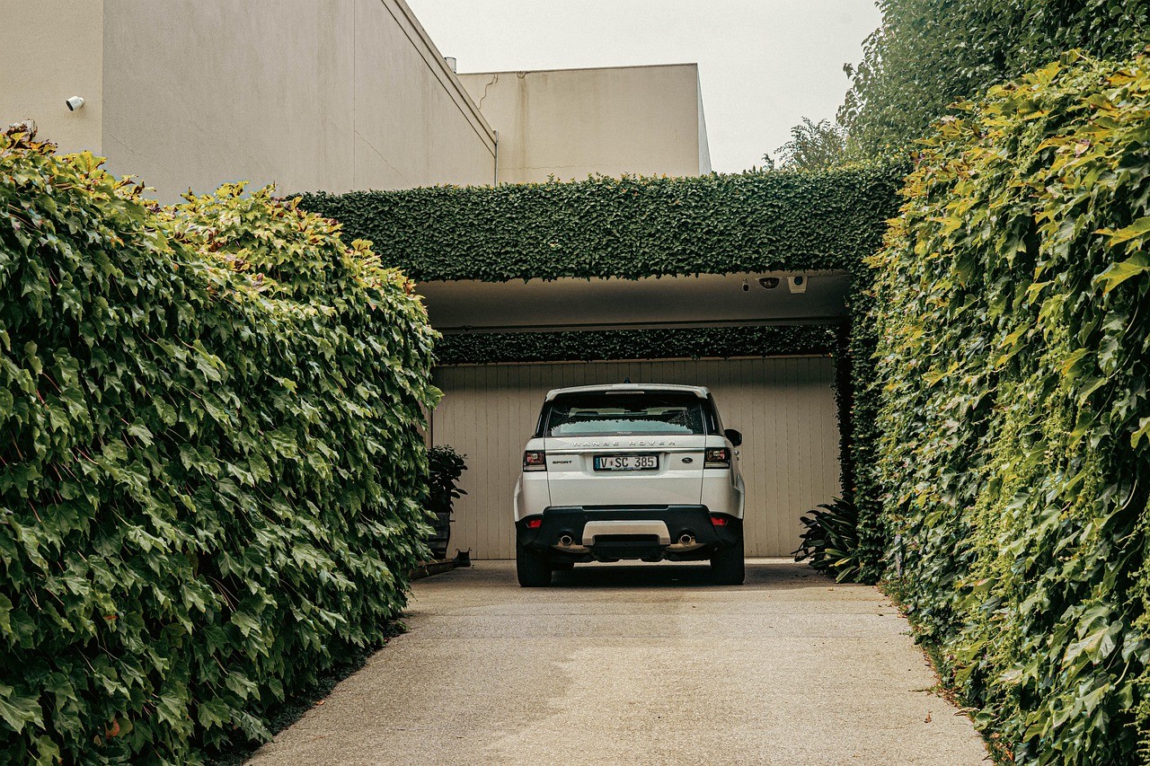 An entry way with well maintained bushes leading to a garage