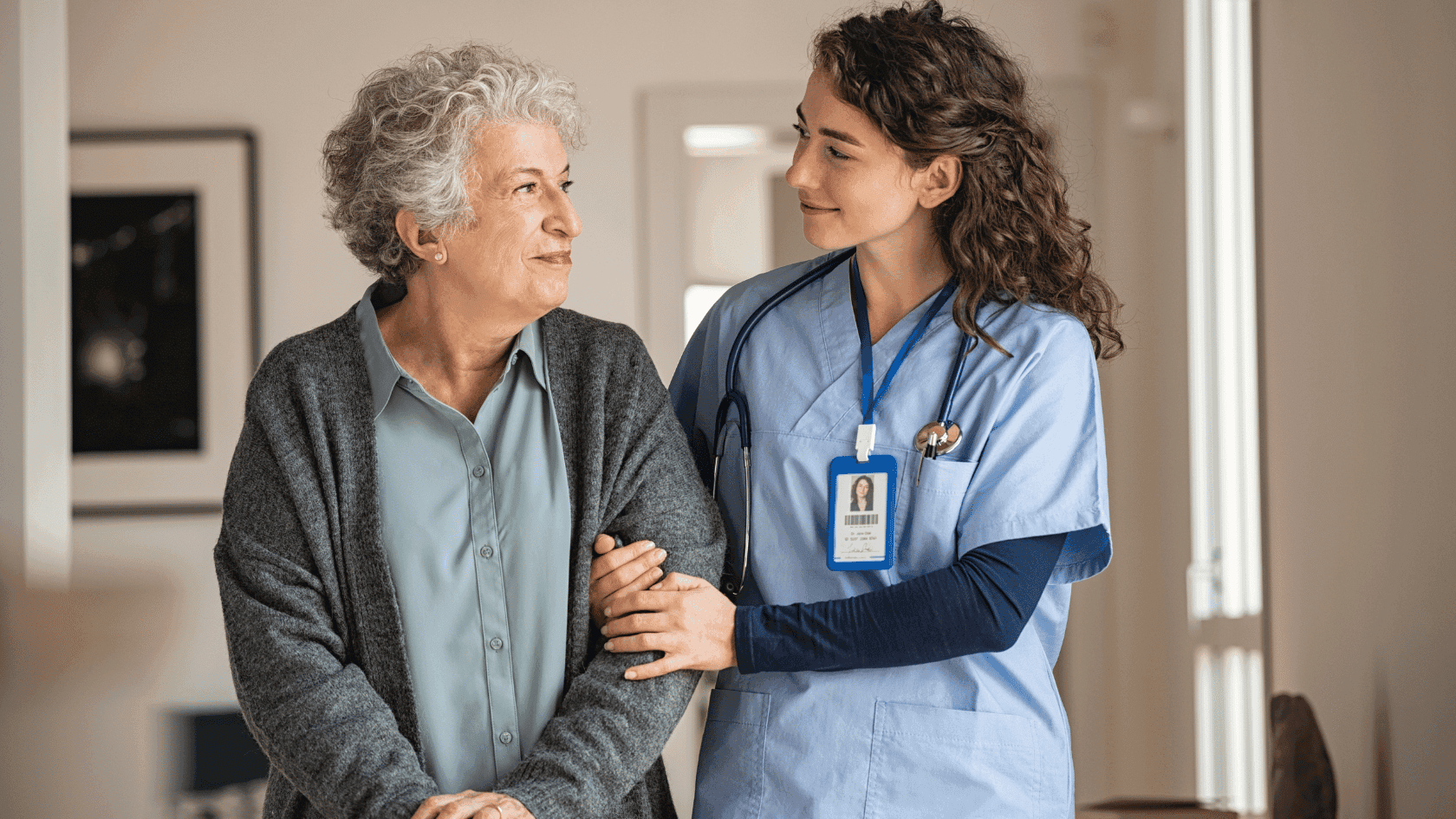 Elderly woman being held up by a nurse.