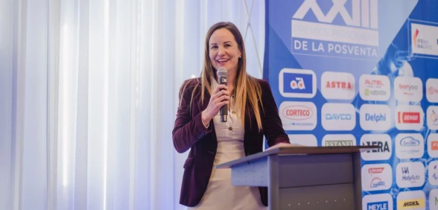 Smiling woman sitting at desk with a computer, surrounded by plants.
