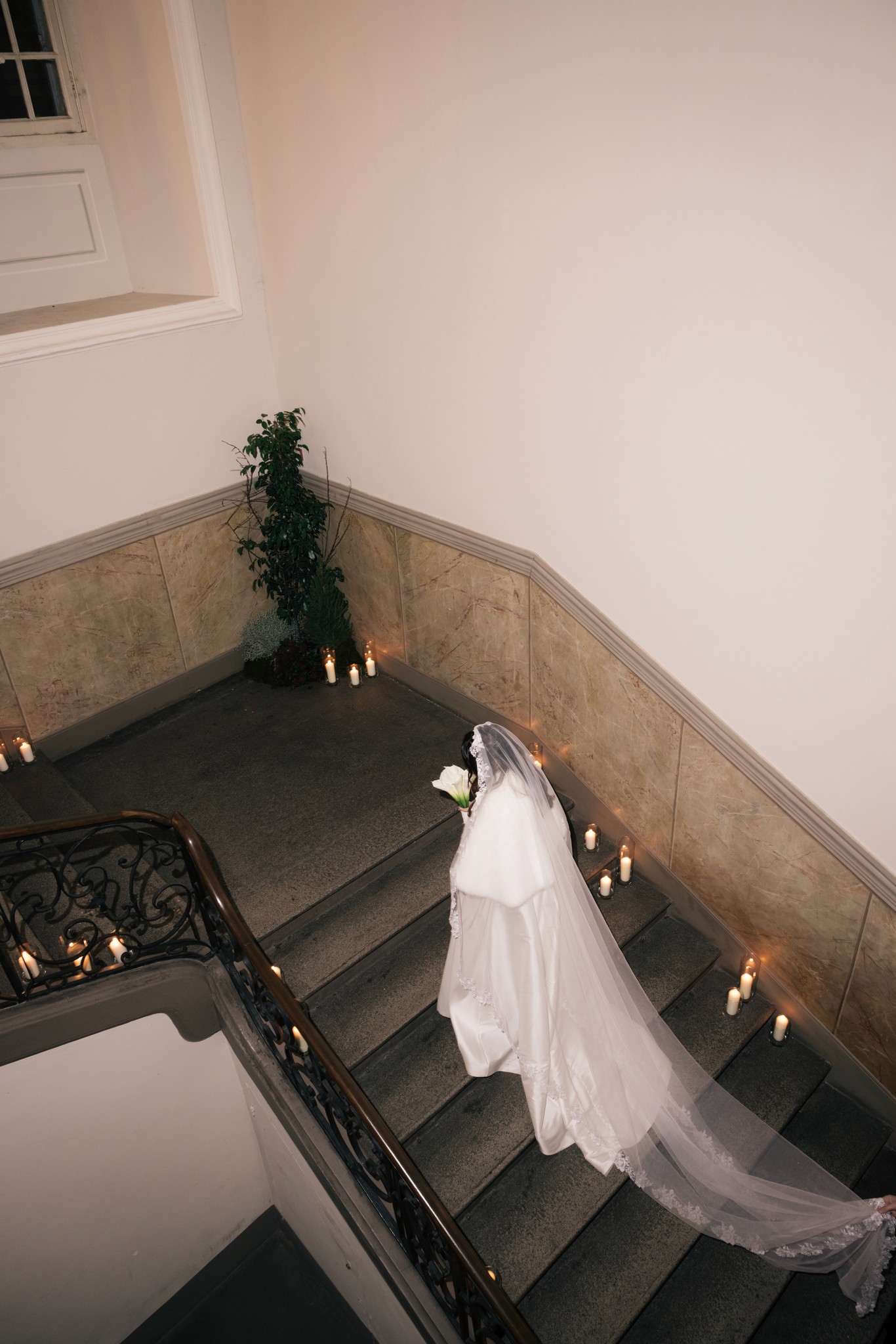 Sposa in abito bianco scende la scala del Circolo di Lettura a Parma, velo lungo e candele sui gradini del matrimonio